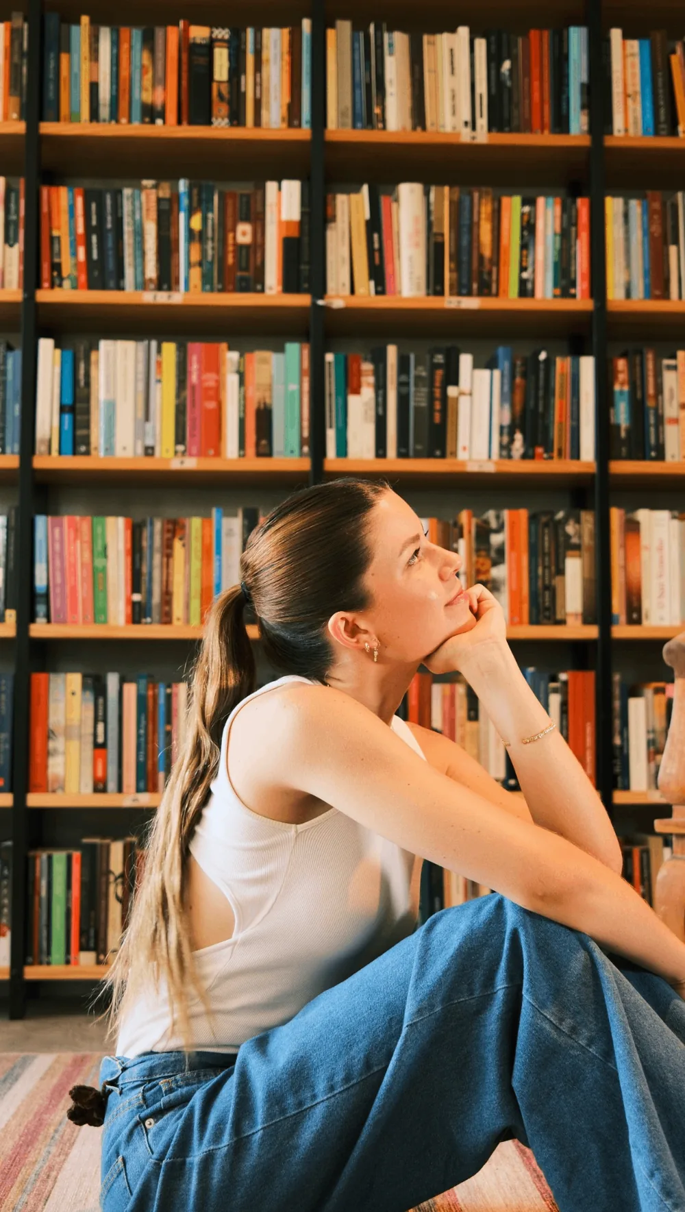 Victória sentada em frente à estante de livros